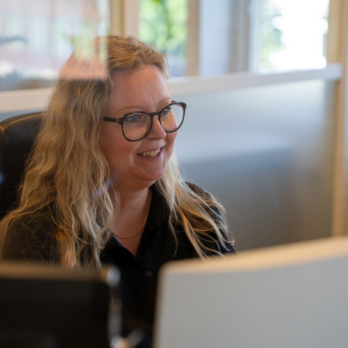 En person som ler och pratar framför en datorskärm.